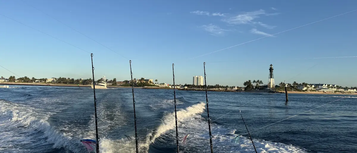 The boat running out of Hillsboro Inlet at first light, rods in the holders and the lighthouse astern