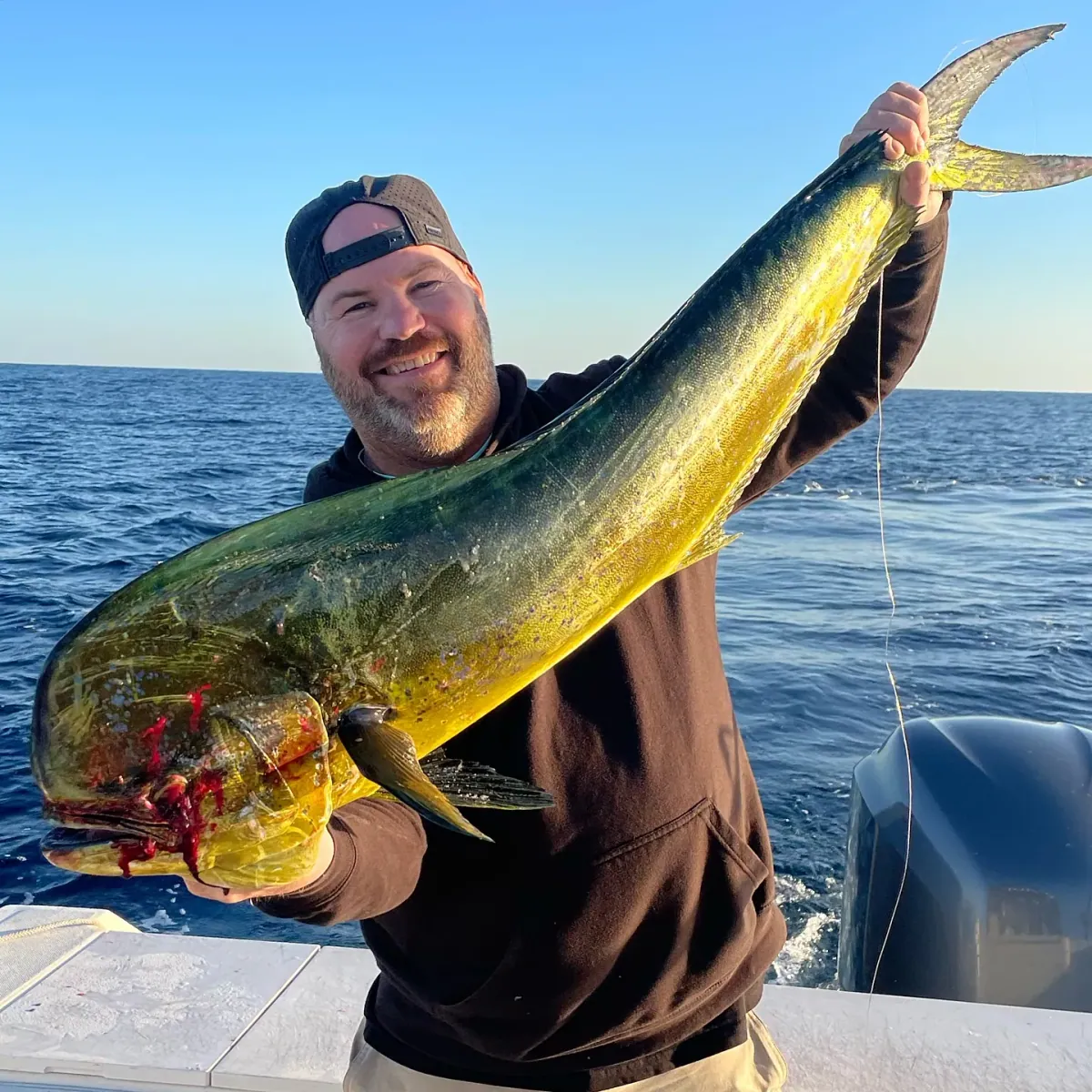 An angler holding up a bull mahi still lit up green and gold