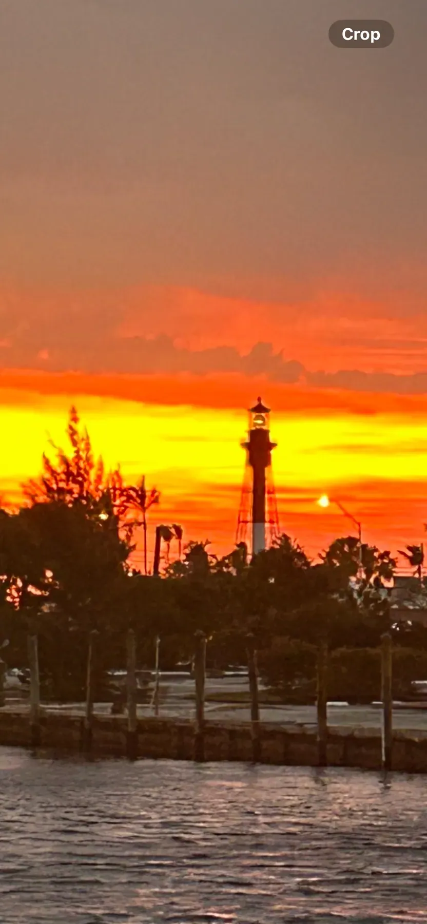 The Hillsboro Inlet lighthouse in silhouette against an orange sunrise