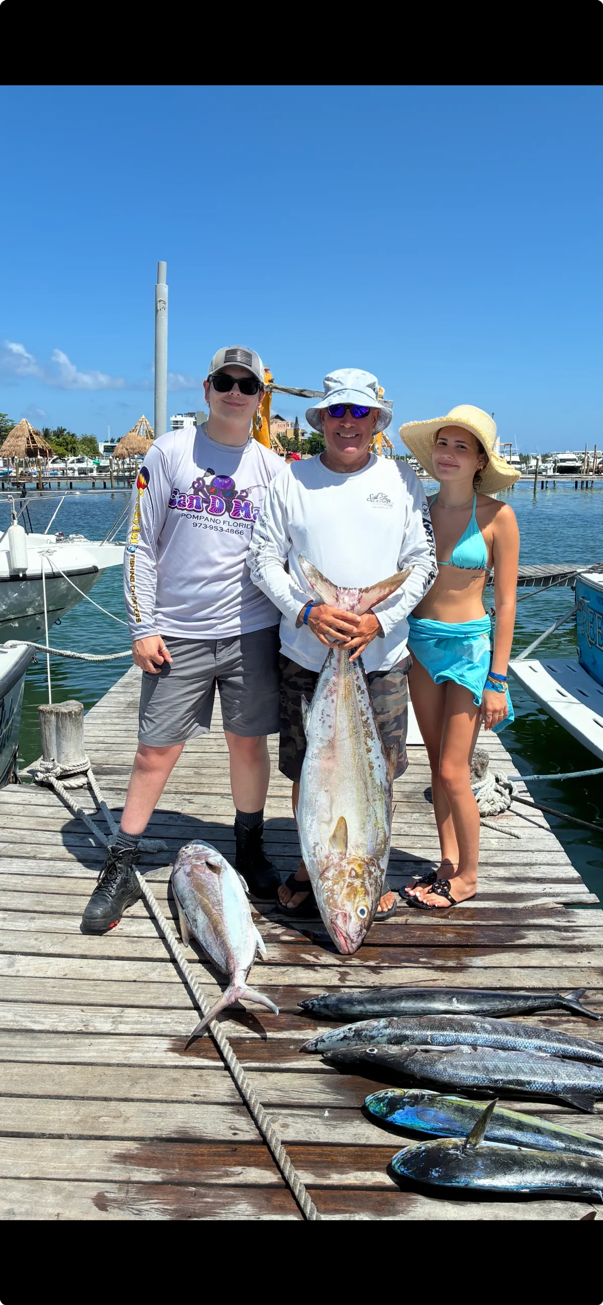 Captain Shawn and two guests on the dock with a big amberjack, wahoo and mahi laid out at their feet