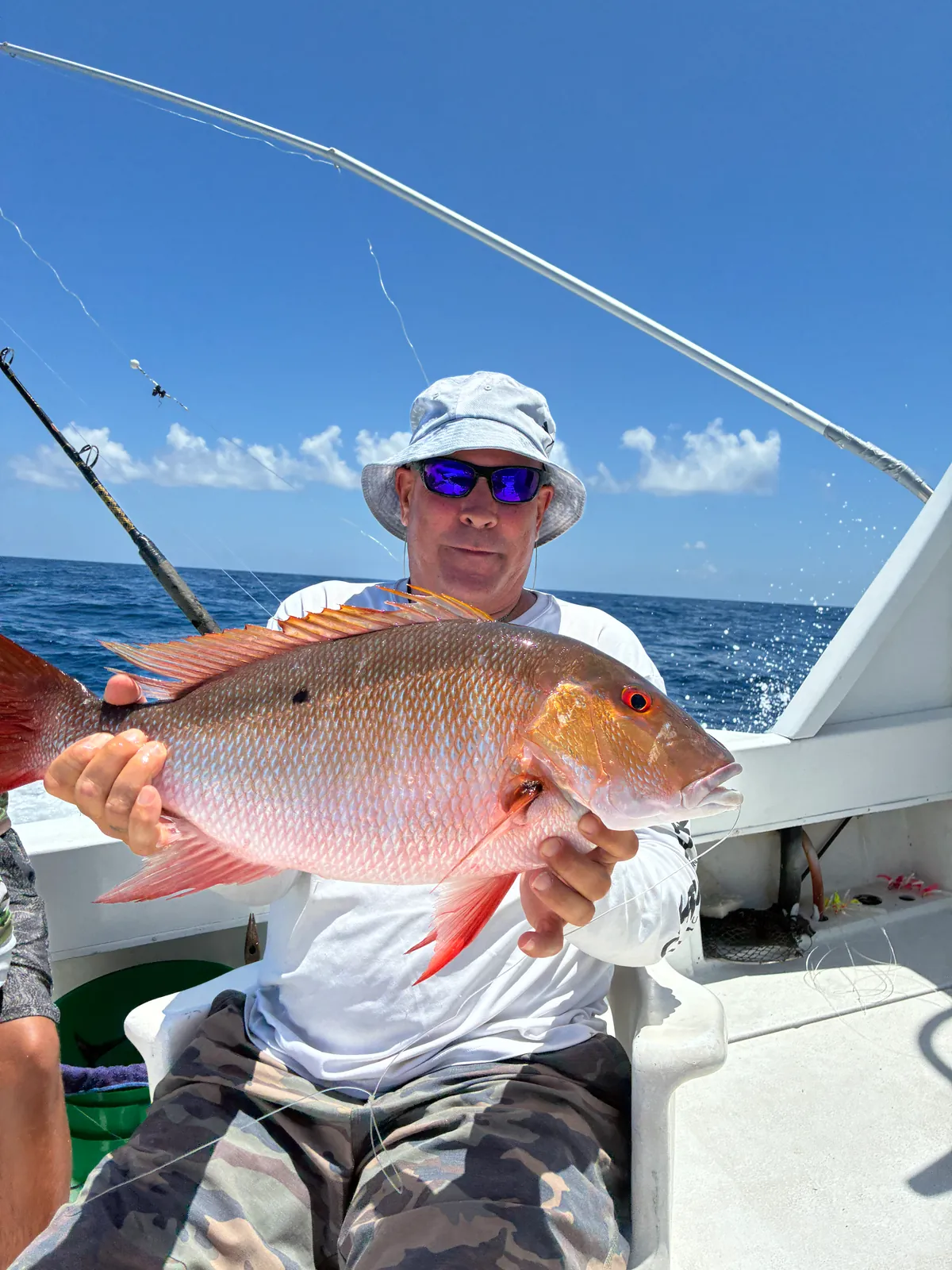 An angler holding a thick mutton snapper at the rail with the blue Atlantic behind