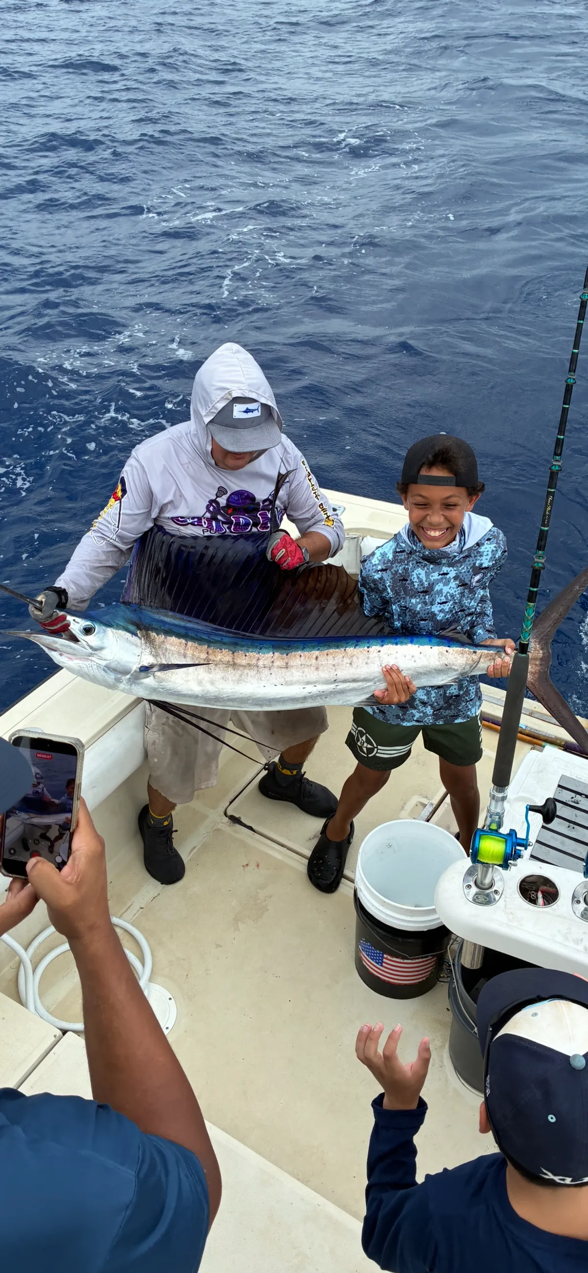 The mate and a young angler holding a sailfish at the rail for a quick photo before the release